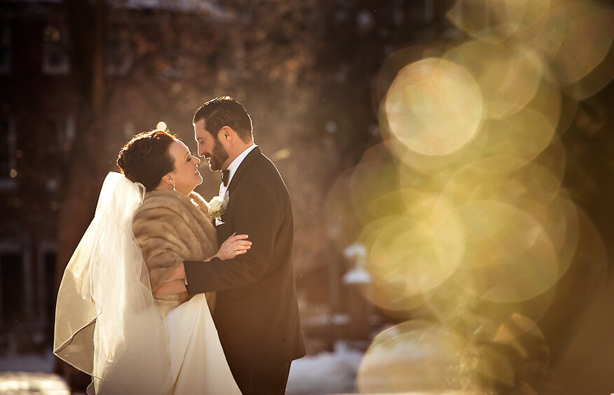 A wedding couple embracing in the snow in front of Palmer.