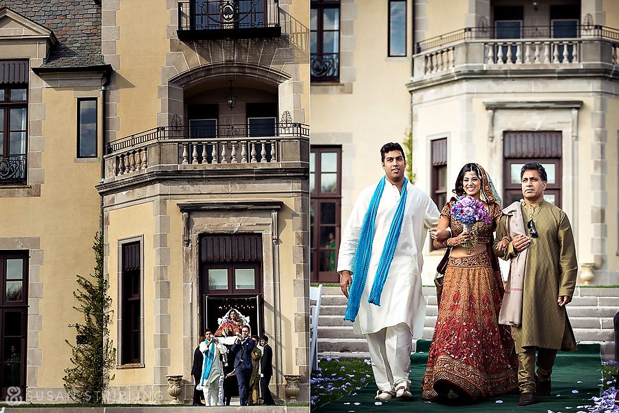 A man and woman dressed in indian clothing are standing outside of a wedding mansion. A man and woman dressed in indian clothing are standing outside of a wedding mansion.