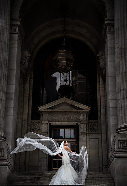 A bride in New York City with her veil blowing in the wind on her wedding day.