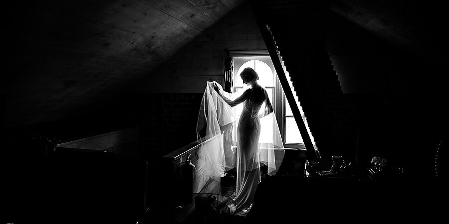 Black and white photo of a bride in a New York City window.
