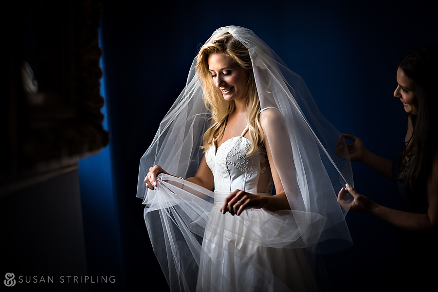 A bride in New York City putting on her veil in front of a mirror.