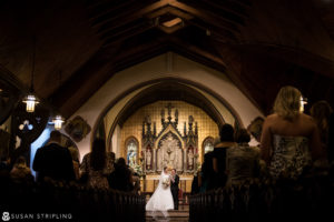 A bride and groom standing in the aisle of a church in New York City, celebrating their wedding.