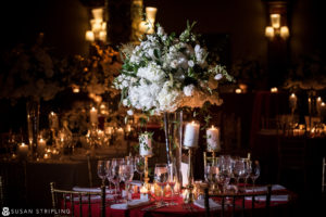 A wedding reception in NYC with candles and flowers on a red table.