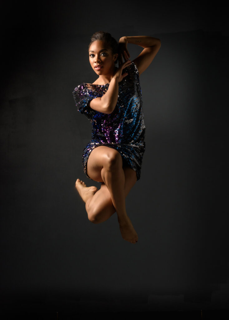 A dancer in a sequined dress jumping in the air at a New York wedding.