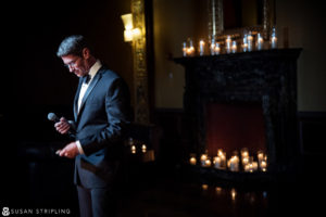 A man in a tuxedo standing in front of candles at a New York City wedding.