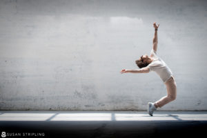 A man is doing a dance in front of a white wall in New York City.