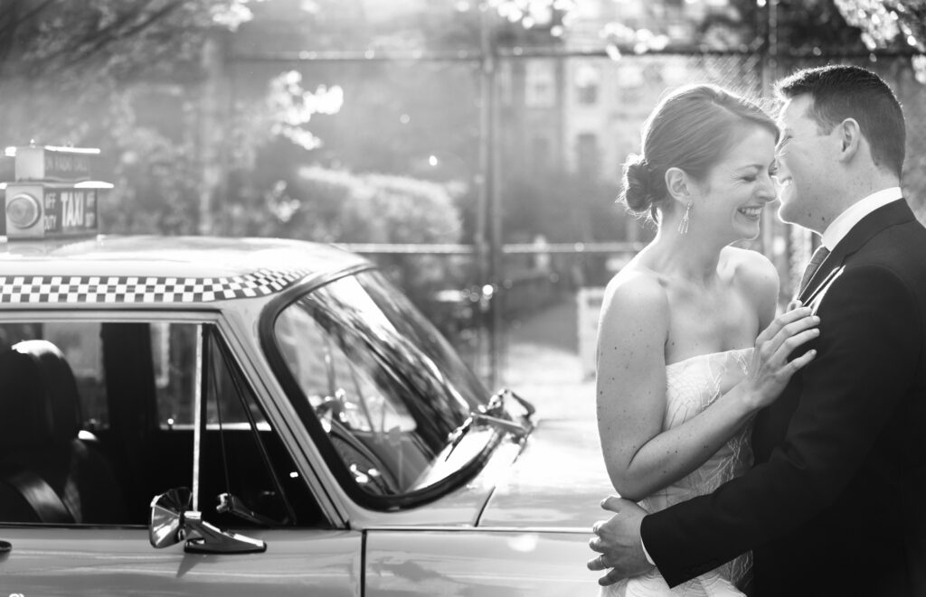 A bride and groom standing next to a New York taxi cab in NYC.