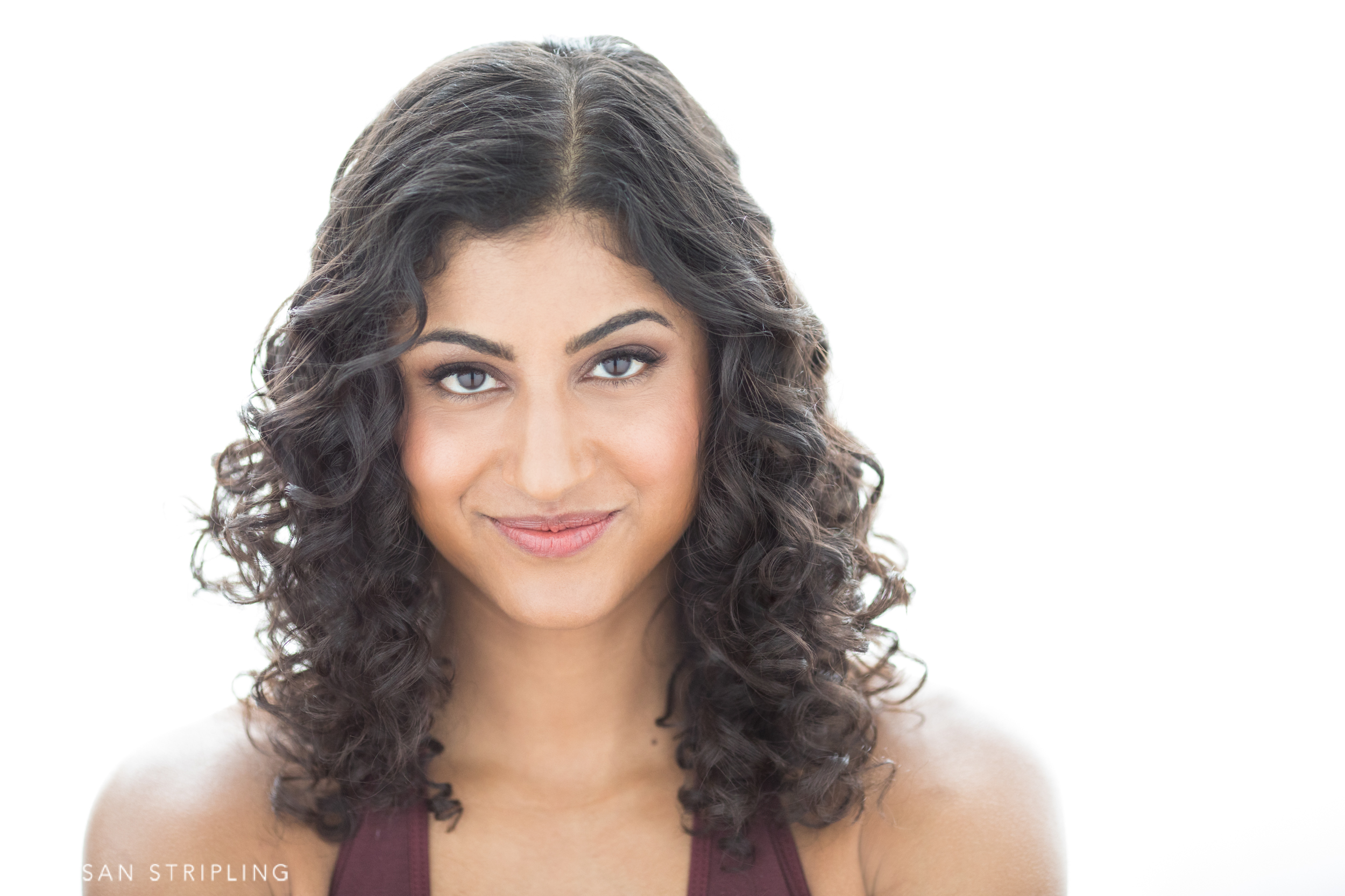 A beautiful woman with curly hair posing for a headshot photo in NYC.