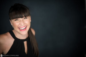 A smiling woman in a black top, suitable for headshots for actors in NYC.