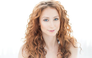 An actress with red hair and blue eyes posing for headshots in NYC.
