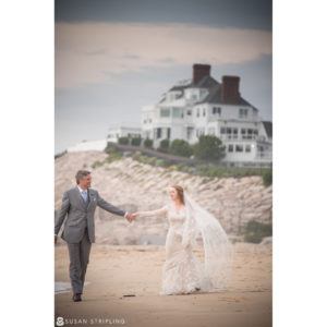 A wedding couple holding hands on the beach of Ocean House in Rhode Island.