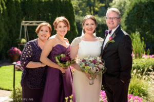 A bride and her bridesmaids pose for a photo while capturing beautiful family pictures at a gorgeous garden wedding.