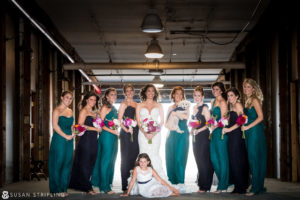 A bride and her bridesmaids pose for a family photo at a wedding.