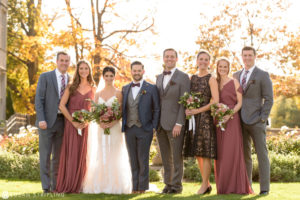 A group of bridesmaids and groomsmen posing for a family photo.