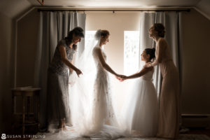 Wedding at Rock Creek Gardens - Bride and bridesmaids holding hands in a room.