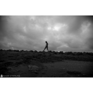 A black and white photo of a person walking on rocks, reminiscent of Game of Thrones.