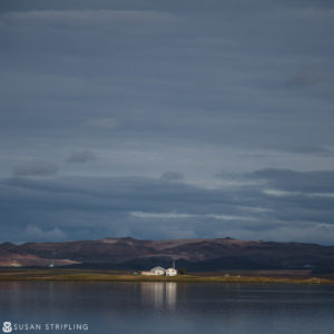 A small white house on the edge of a body of water, reminiscent of Game of Thrones location photos.