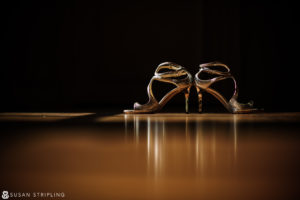 A pair of high heeled shoes on a wooden floor at an Outdoor Wedding at Oheka Castle.