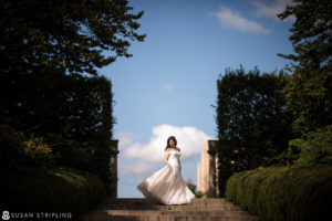 Fall Wedding at the Brooklyn Botanic Garden: A bride in a white dress standing on steps in a garden.