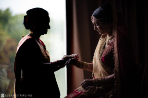 An Indian bride is putting on her wedding ring during her New Jersey wedding.