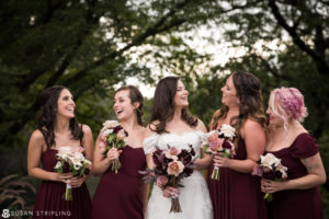 A group of bridesmaids laughing and holding their bouquets at a Fall Wedding at the Brooklyn Botanic Garden.