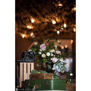 An elegant table adorned with a striking vase of flowers, accompanied by a vintage old suitcase.