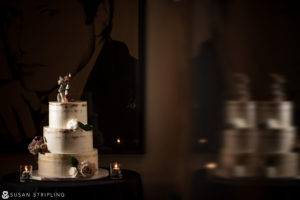 A wedding cake sitting on a table in front of a painting at the Gramercy Park Hotel.