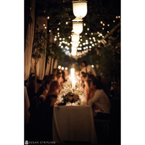 A wedding party sitting at a long table under string lights at the Gramercy Park Hotel.
