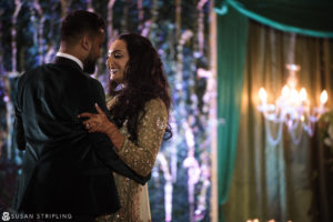 A New Jersey bride and groom embracing in front of a chandelier at their Indian wedding.