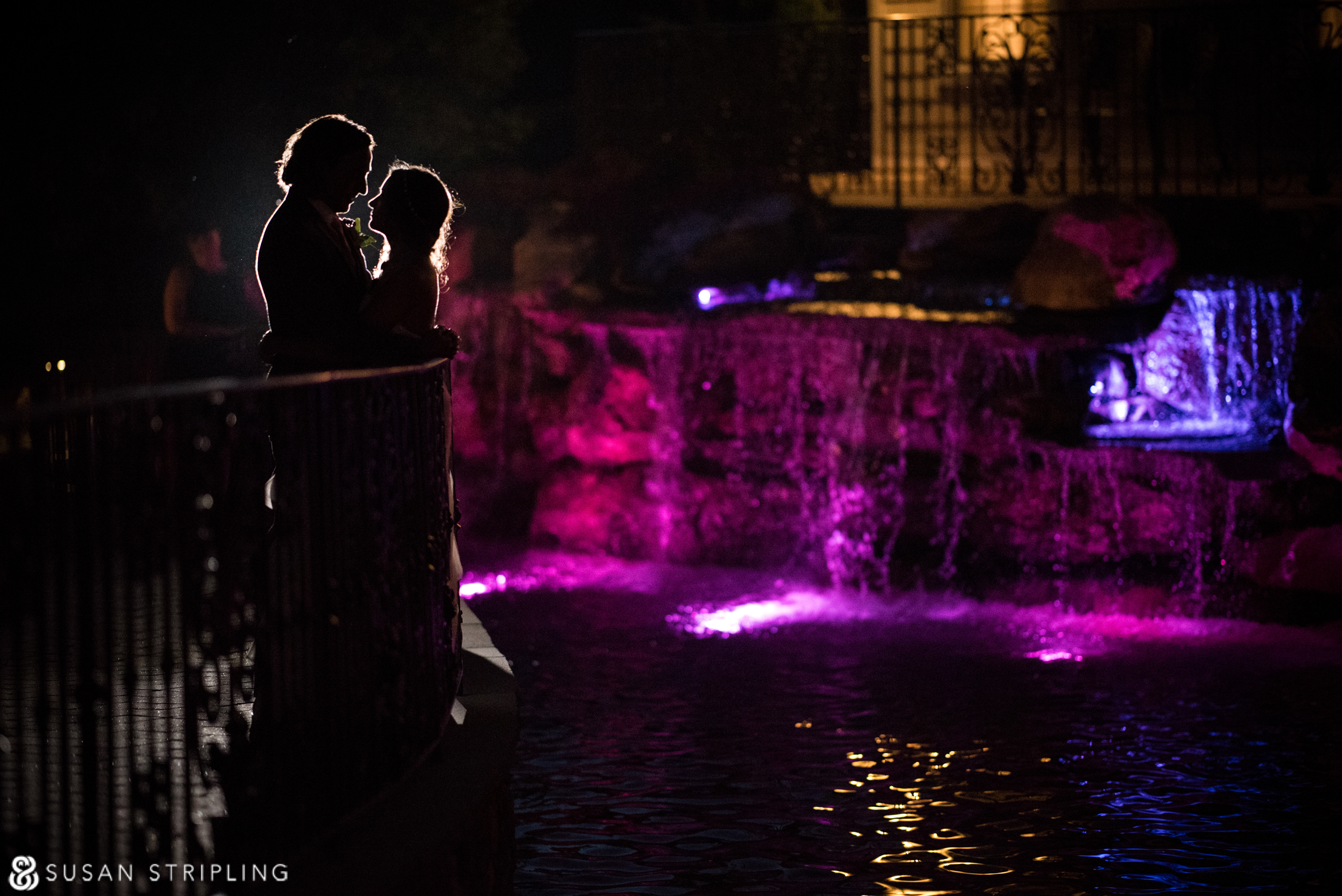 A summer wedding at the West Hills Country Club, with the bride and groom standing in front of a waterfall at night.