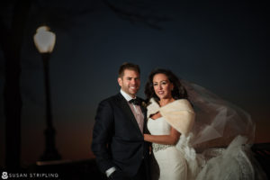 A bride and groom posing in front of a light at night during their wedding at Current Chelsea Piers.