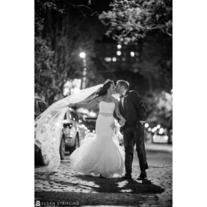 A bride and groom kissing on the street at night during their wedding at Current Chelsea Piers.