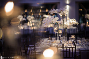 A table with white orchids in a glass vase at a wedding at Current Chelsea Piers.