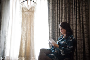 A bride reading her wedding dress in front of a window for her New Year's Eve wedding.