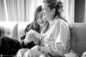 Two women sitting on a couch reading a book at Cescaphe Philadelphia wedding.