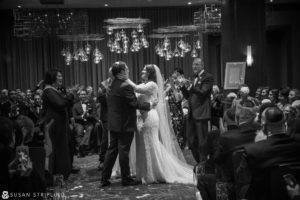 A bride and groom hugging at their New Year's Eve wedding in front of a crowd.
