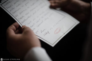 A man at a Cescaphe Philadelphia wedding, holding a piece of paper with a handwritten note.