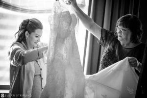 A woman is assisting her mother with a Cescaphe Philadelphia wedding dress fitting.