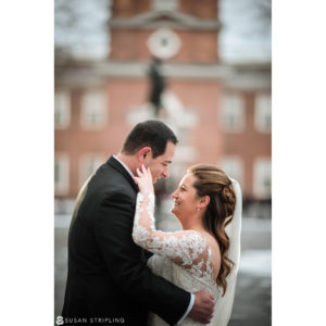 A Cescaphe Philadelphia wedding - the bride and groom embrace in front of a clock tower.