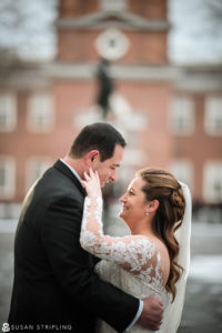 A bride and groom embrace in front of the clock tower at a Cescaphe Philadelphia wedding.