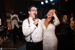 A bride and groom joyfully singing into a microphone at a New Year's Eve wedding reception.
