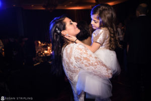 At a heartwarming New Year's Eve wedding reception, a little girl is joyfully hugging her mother.