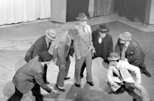 A group of men in suits and hats, including a Canon Explorer of Light, on a stage.