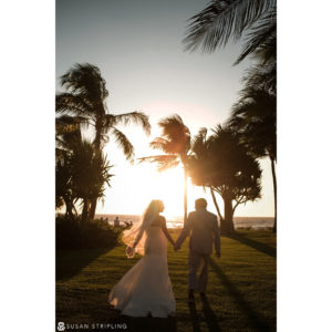 A Canon Explorer of Light captures the romantic moment as a bride and groom walk along the beach at sunset.