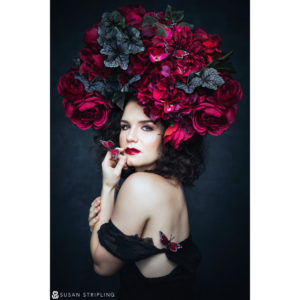 A Canon Explorer of Light adorned with red flowers on her head.