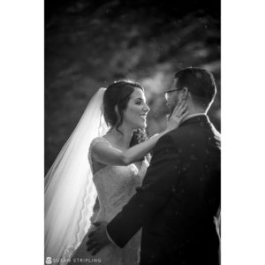 A bride and groom sharing a romantic kiss in the rain during their wedding at the Madison Hotel.
