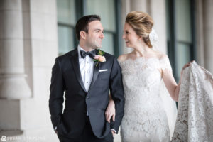 A destination wedding photographer captures a beaming bride and groom in front of a stunning building.
