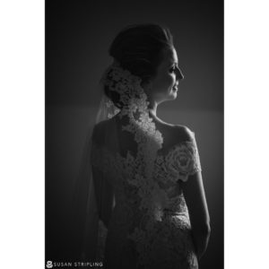 A destination wedding photographer captures a stunning black and white photo of a bride in her exquisite lace dress.