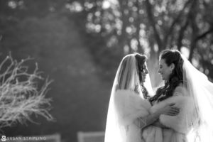 Two brides hugging in front of a tree during their wedding at Shadowbrook at Shrewsbury.