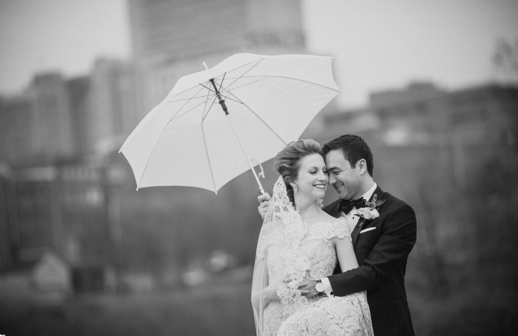 A destination wedding photographer captures the intimate moment of a bride and groom embracing under an umbrella.